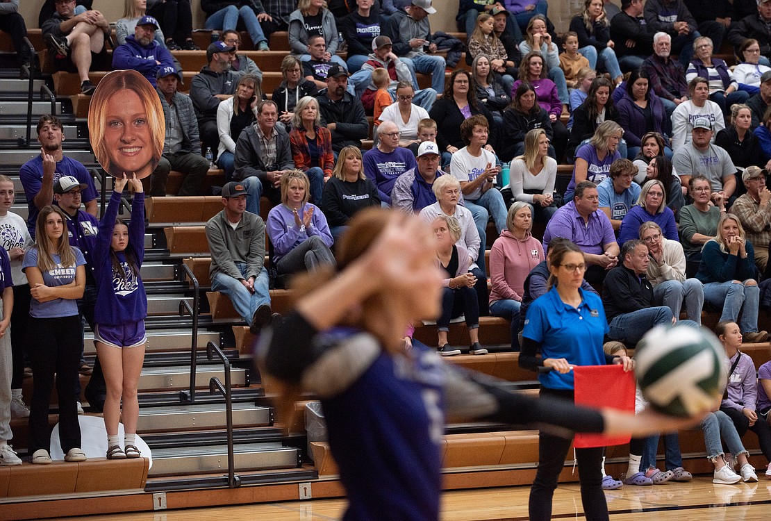 Nooksack Valley senior rightside hitter Cailyn Likkel prepares to serve. A cutout of her head is held up behind her.