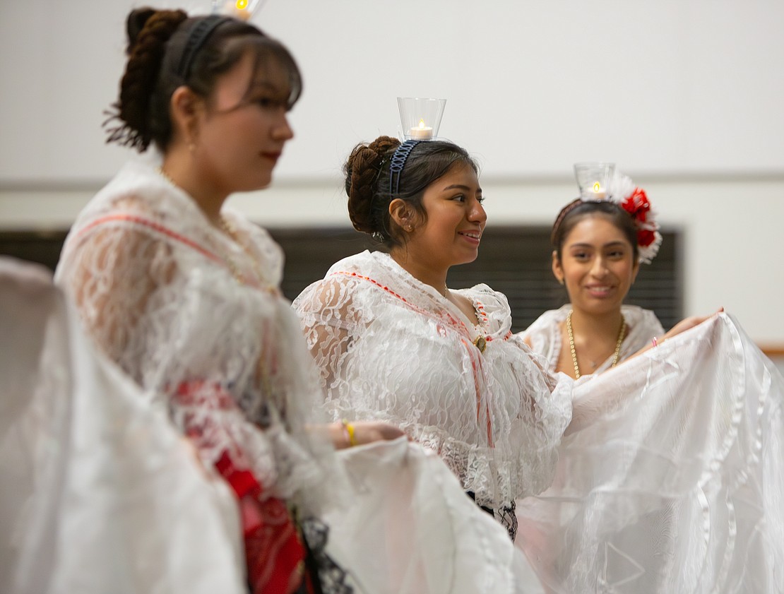 Students perform the traditional dance "La Bruja" (the witch), donning white dresses and LED candles on their heads.