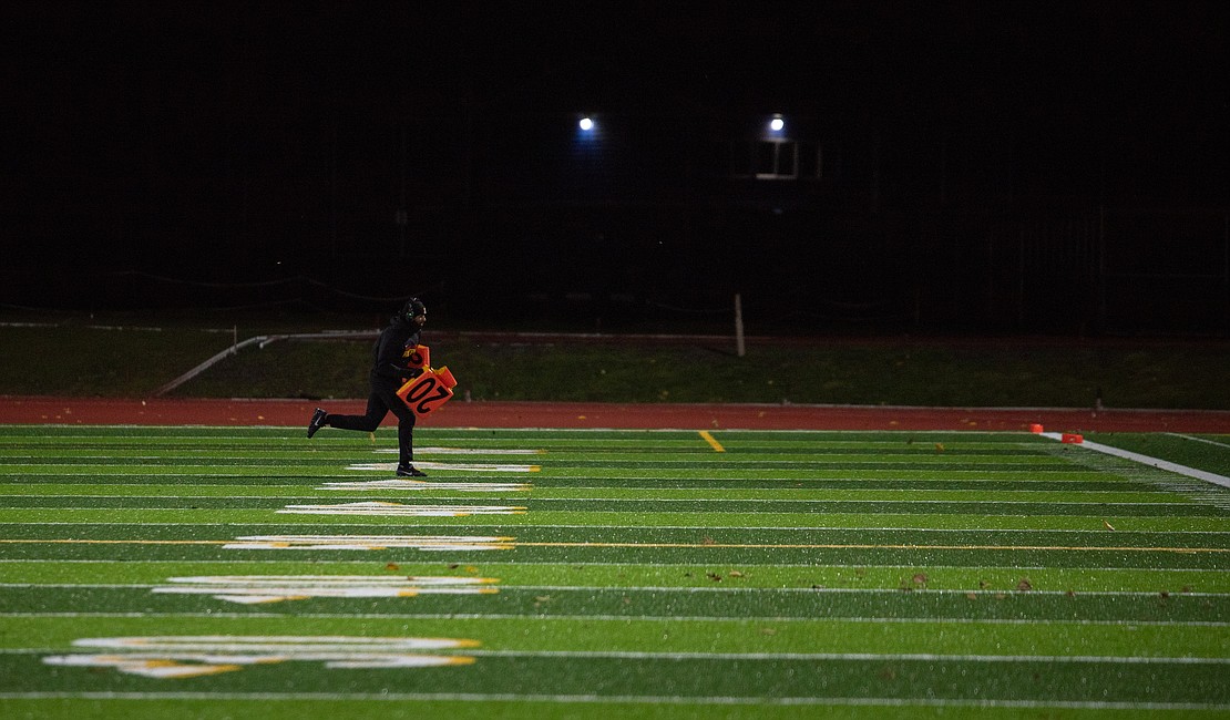 A Mount Tahoma coach runs yard markers back to the sideline after they were blown onto the field.