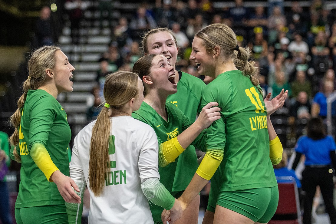 Lynden's Haylee Koetje, middle, grabs Rian Stephan in celebration Friday, Nov. 10 after the Lions swept Sammamish in the opening round of the 2A state tournament at the Yakima Valley SunDome.