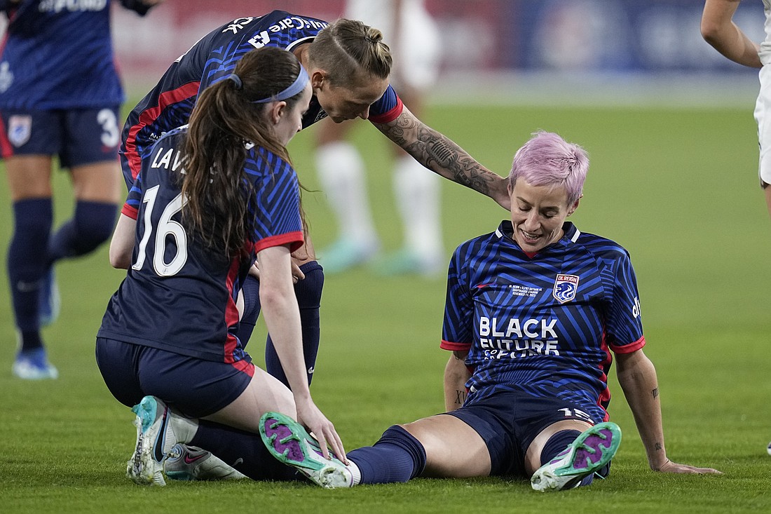 OL Reign forward Megan Rapinoe, right, stays down after an injury as teammates midfielder Rose Lavelle (16) and midfielder Jess Fishlock, center, check on her Saturday, Nov. 11 in San Diego. Gotham FC won the NWSL Championship game 2-1.