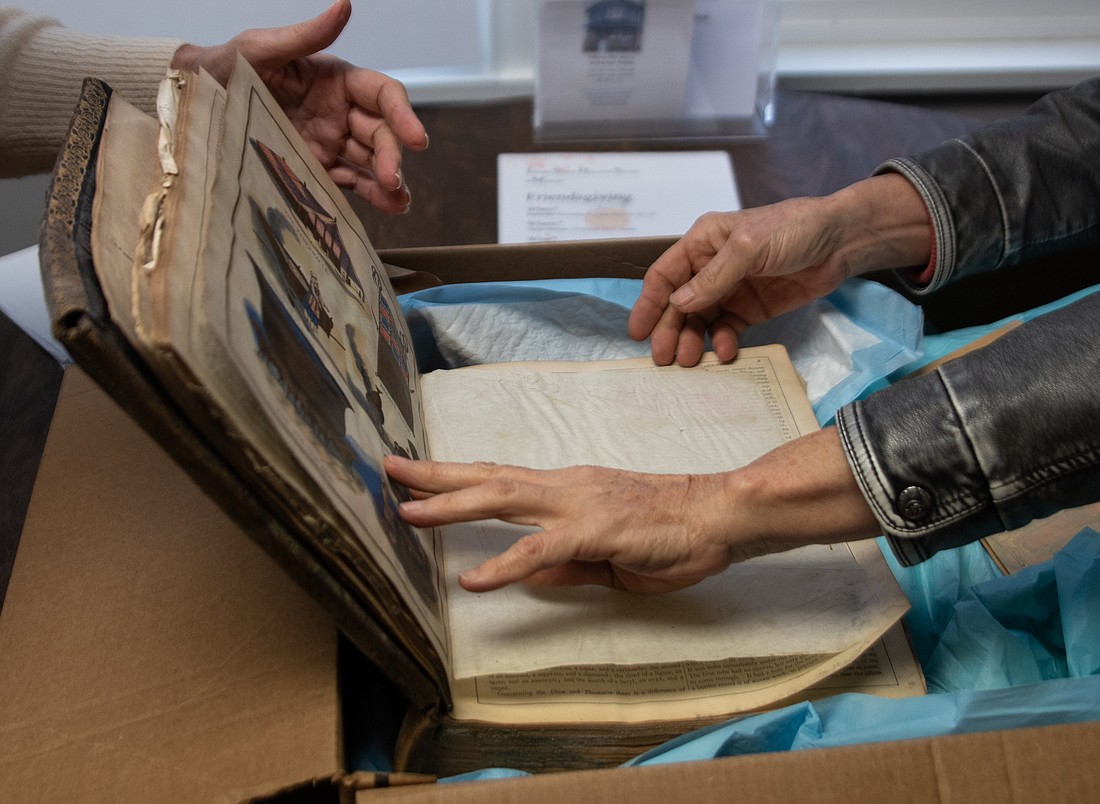 Sumas Museum President Liz Custer, left, and Secretary Helen Solem flip through what they call the museum's biggest loss in the 2021 flood — a 19th-century Bible. It had been wrapped in dog training pads to help absorb moisture.