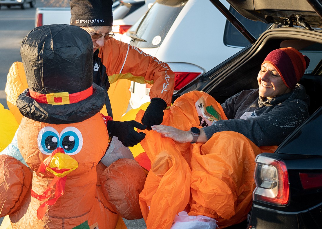 Muriel Handschy, left, and her partner, Becky Prikril, try to put Prikril's inflatable turkey costume over her right foot.